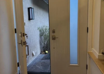 Interior view of a modern open door revealing an outdoor pathway, with a soft light illuminating the entryway.